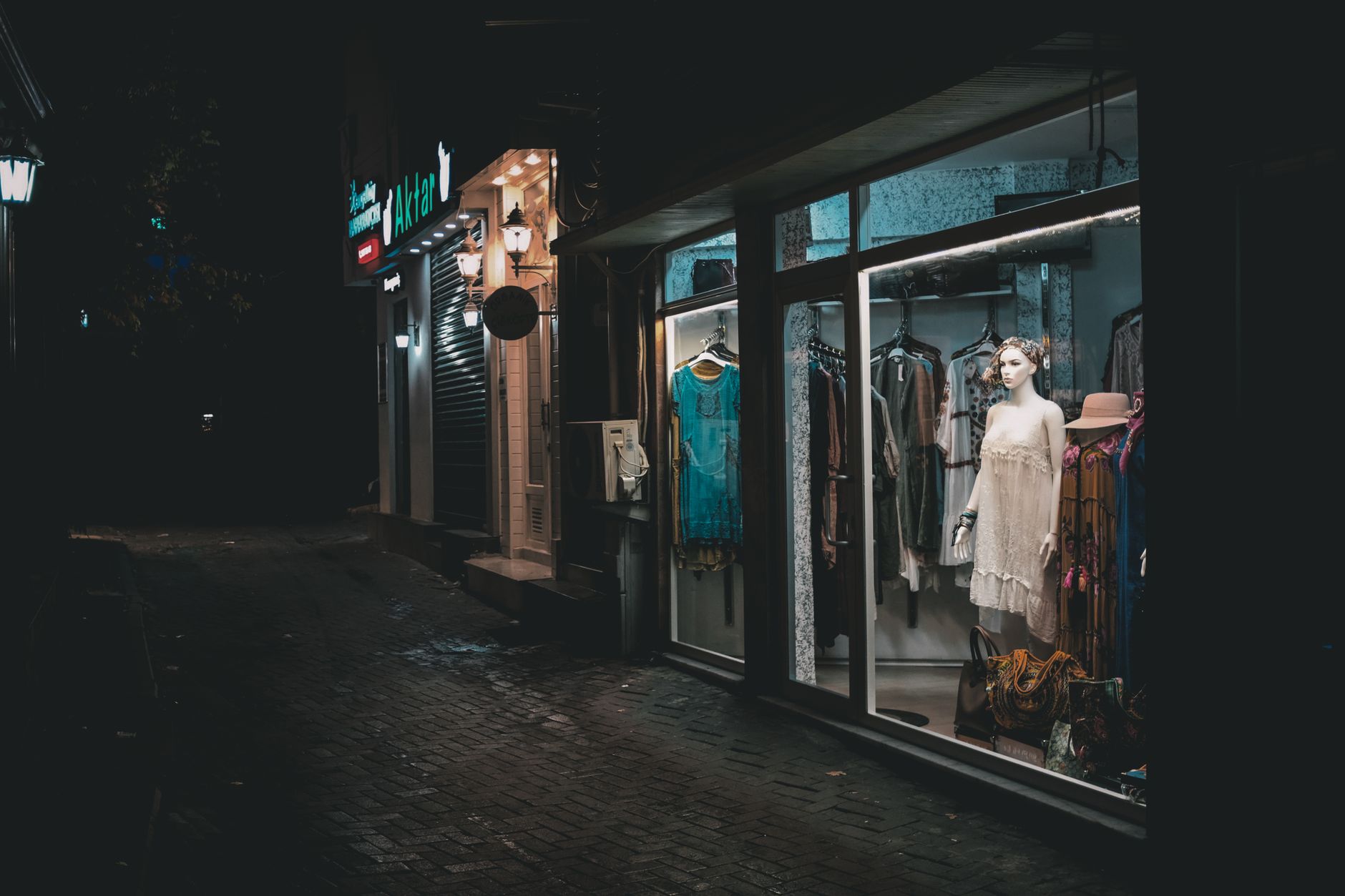 Elegancka witryna butikowa z sukienkami oświetlona nocą w wąskiej uliczce