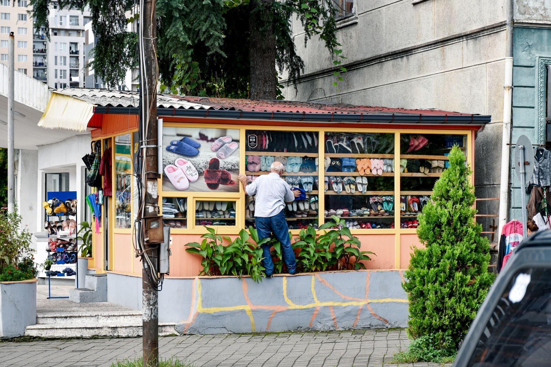 Mężczyzna ogląda kolorowe buty na barwnym ulicznym stoisku z obuwiem