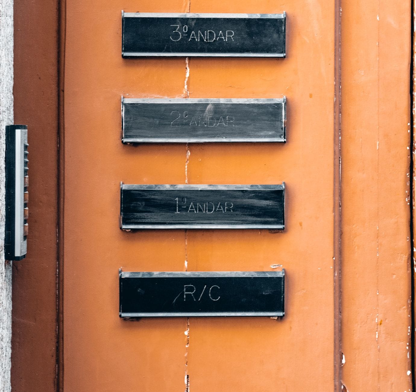 Wejście do budynku z oznaczeniami pięter na pomarańczowej ścianie